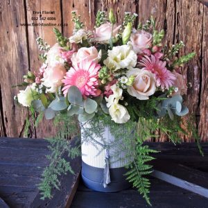 Classic pastel hat box arrangement of seasonal flowers, including roses