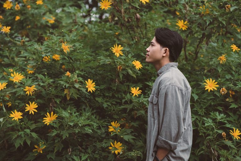 A man enjoying some wild flowers, gifting flowers for men can bring them the same enjoyment and mood improvement