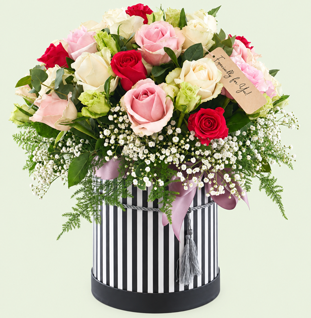 Shades of pink and cream roses in a black and white striped hatbox