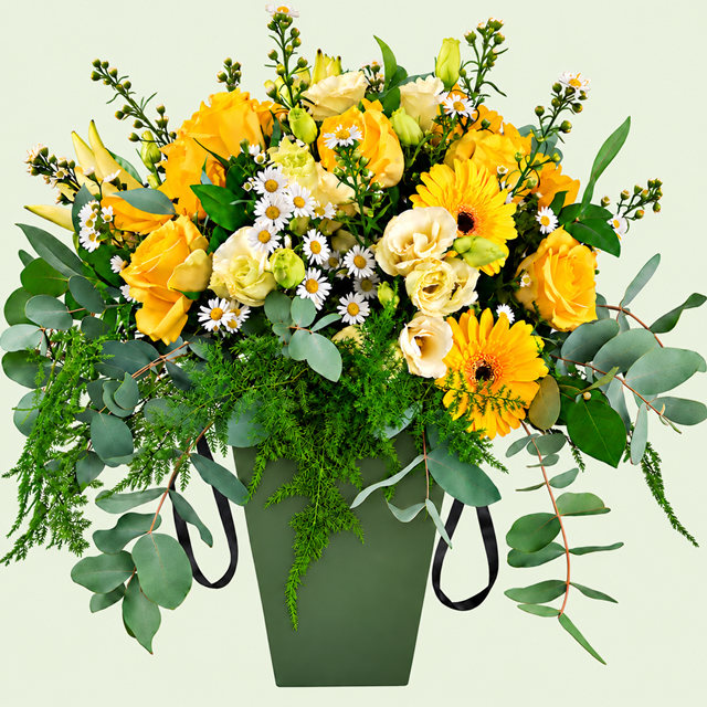 Yellow and cream seasonal flowers in a moss green box with black satin ribbon handles