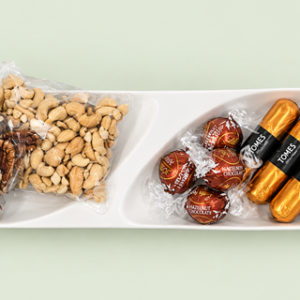 A selection of nuts and chocolates on a ceramic dish to keep and reuse for serving snacks.