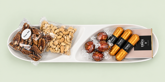 A selection of nuts and chocolates on a ceramic dish to keep and reuse for serving snacks.